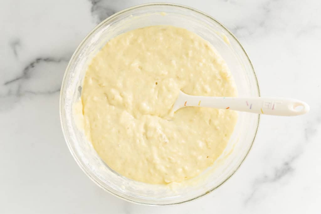 Batter for banana yogurt pancakes in glass bowl.