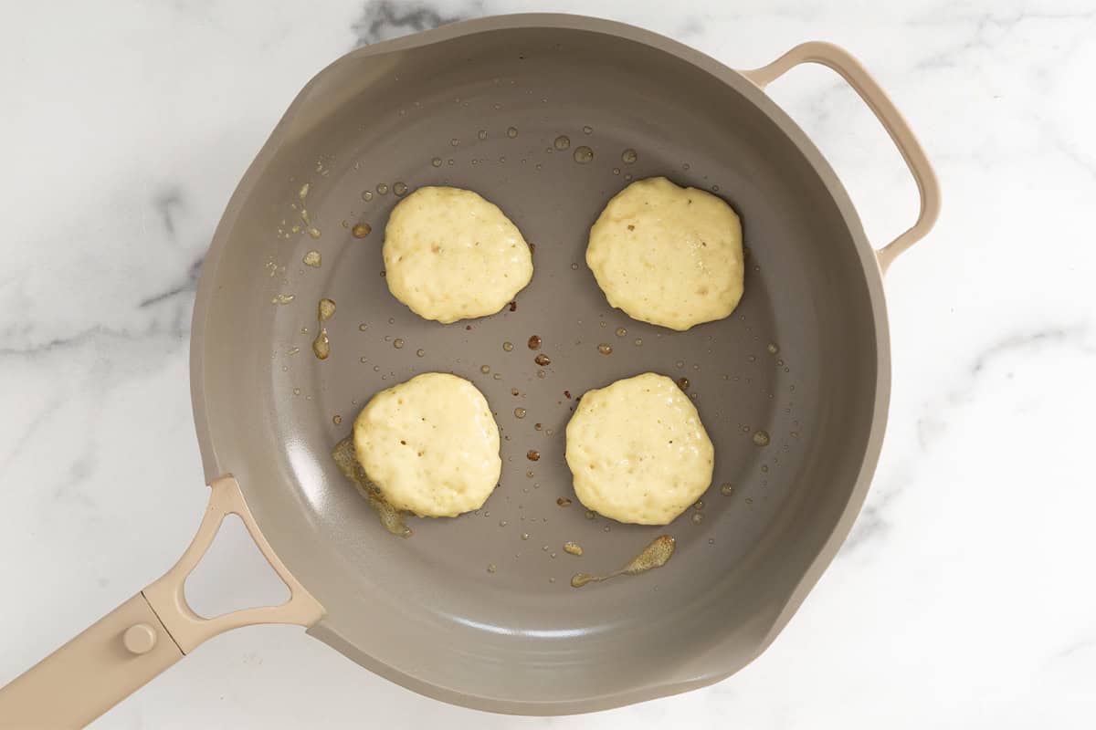 Banana yogurt pancakes in pan before flipping.