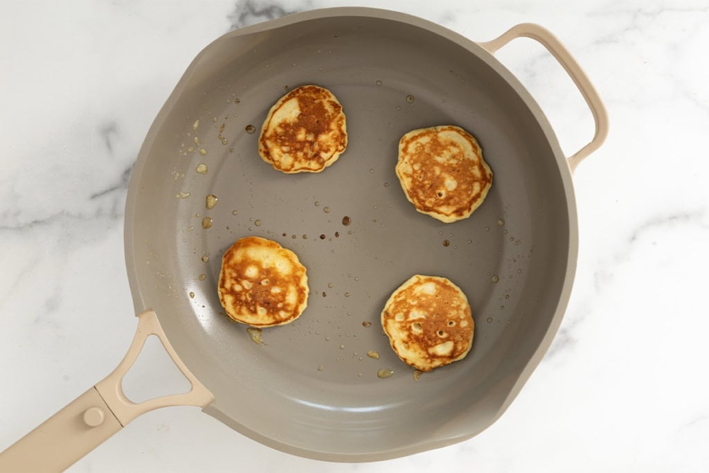 Banana yogurt pancakes in pan after flipping.