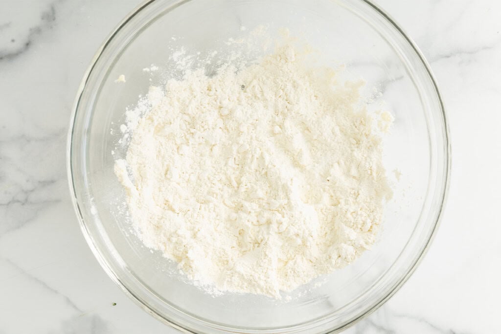 Flour and butter mixed together in glass bowl for biscuits.