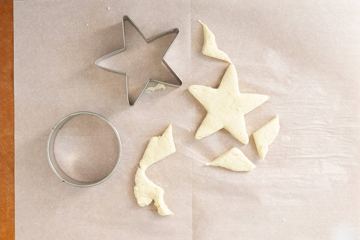 Cutting out biscuit with star and circle shaped cookie cutter.