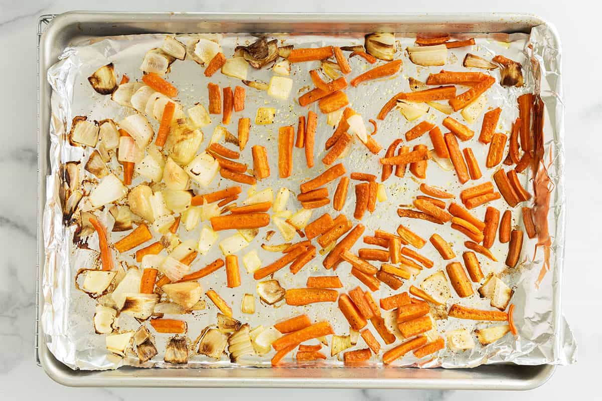 Carrots and onions on baking sheet after roasting.