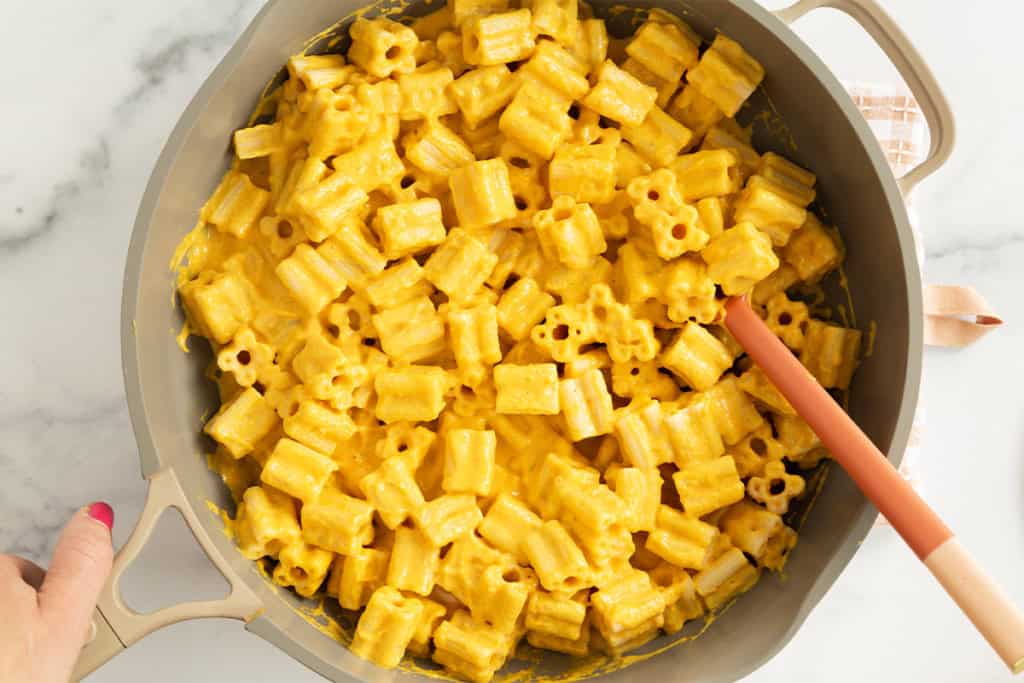Carrot pasta in pot with spoon.