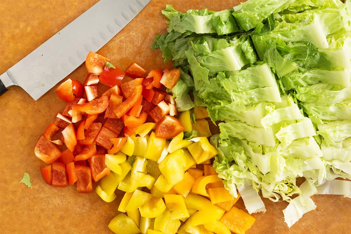 Chopped veggies on cutting board for pizza salad.