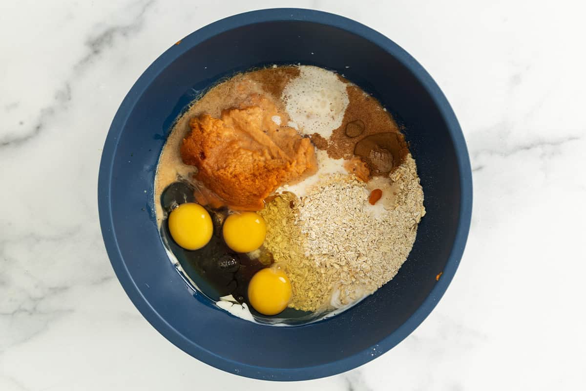 Pumpkin baked oatmeal ingredients in blue bowl before mixing.