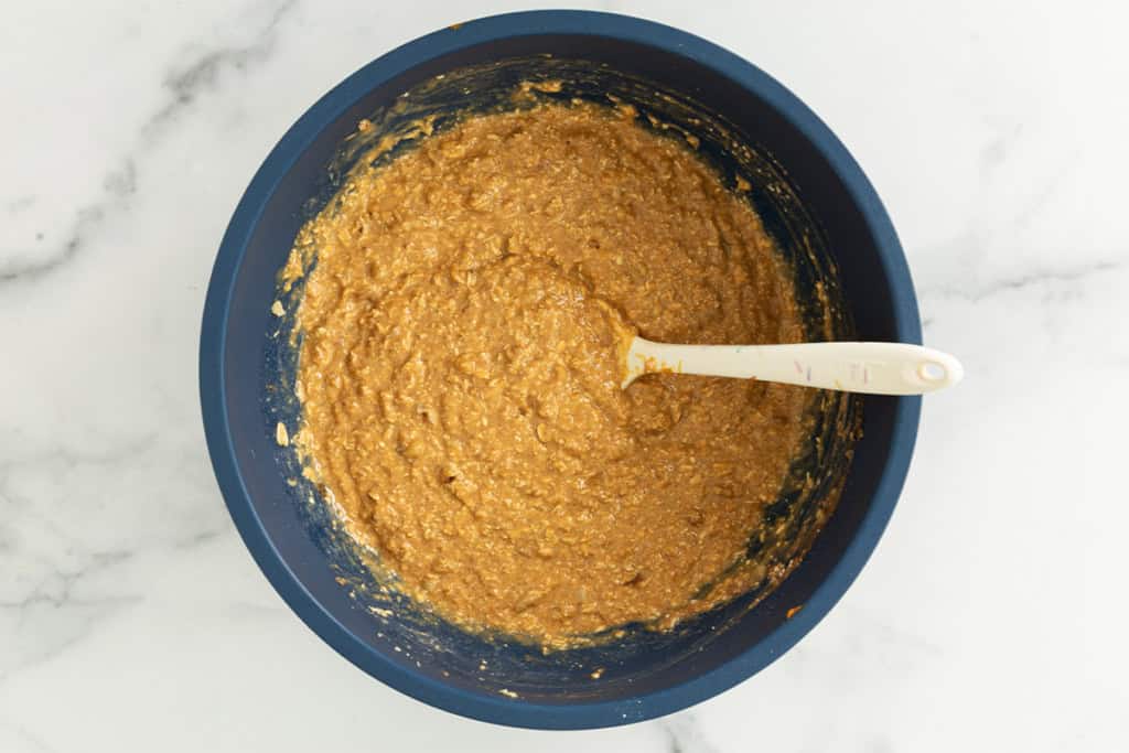 Batter for pumpkin baked oatmeal in blue bowl with spoon.