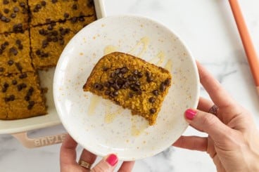 Pumpkin baked oatmeal on white plate with honey drizzle.