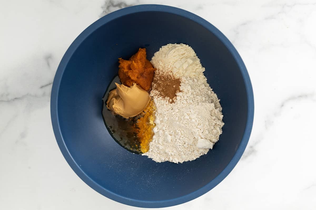 Ingredients for pumpkin protein balls in blue bowl before mixing.