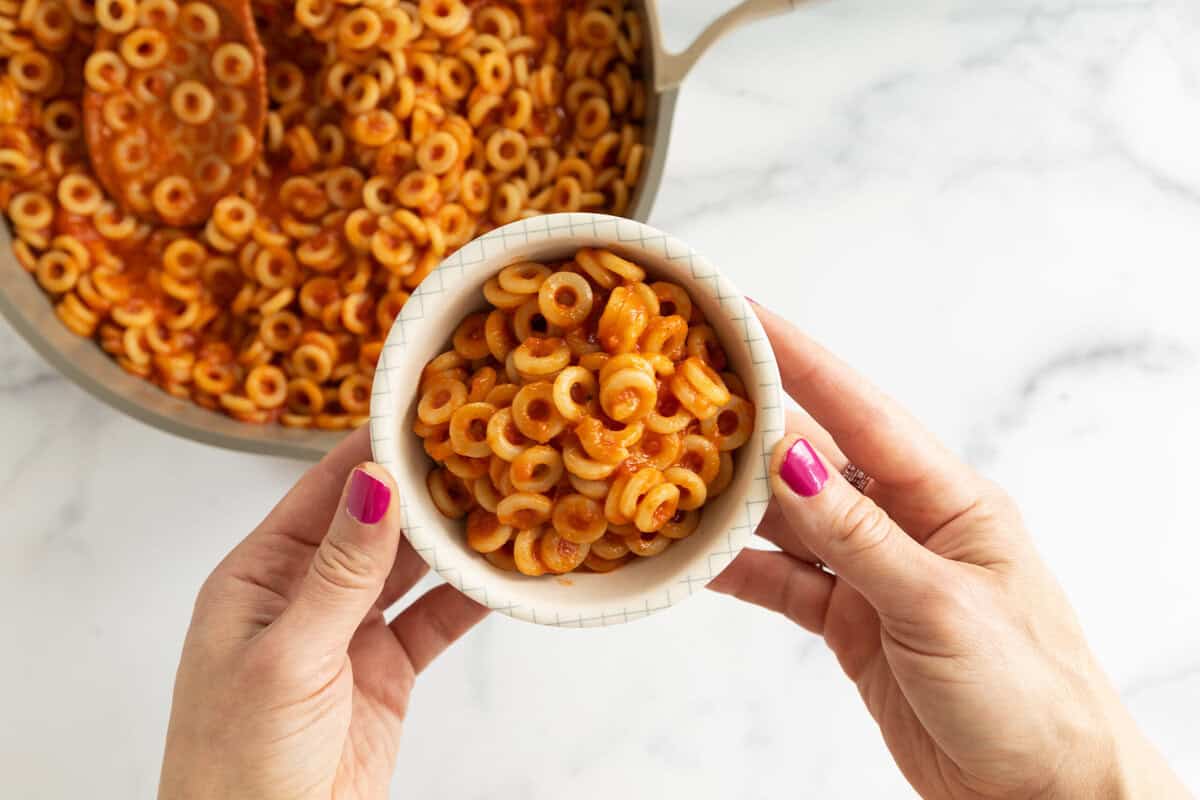 spaghettios in bowl with woman's hand.