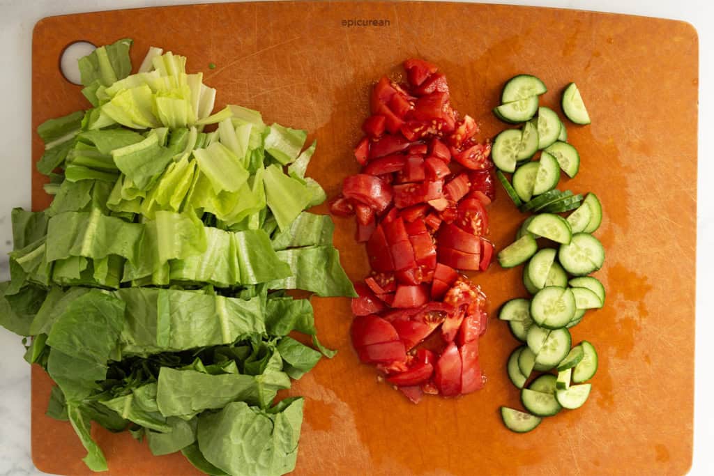 Veggies chopped on cutting board for cheeseburger salad.