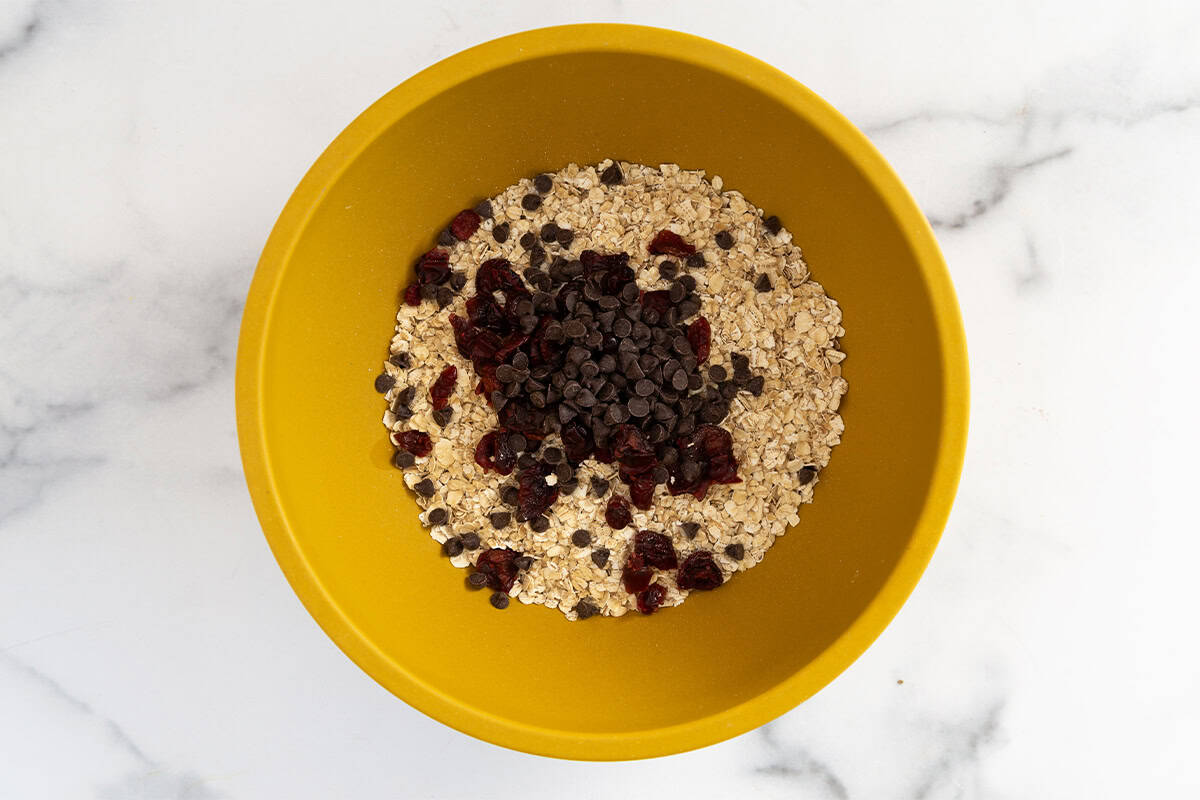 Ingredients for almond butter protein balls in yellow bowl.
