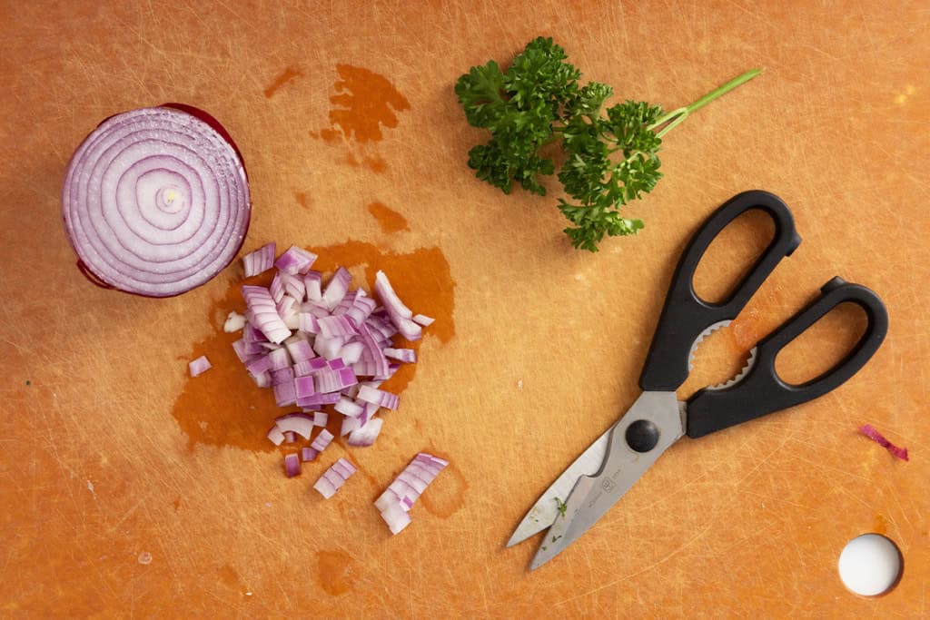 Onion and parsley on cutting board for chicken salad.