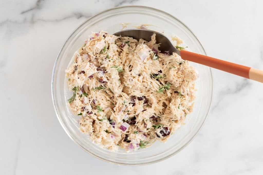 Chicken salad in glass bowl with spoon.