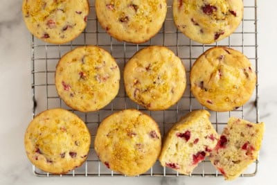 Cranberry muffins on cooling rack with one cut in half.