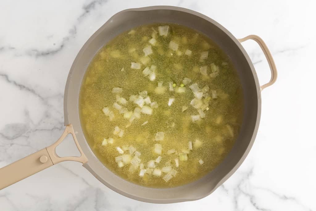 Onions and broth in pot for broccoli cheddar soup.