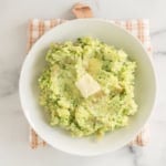Mashed potatoes with broccoli on plate with butter.
