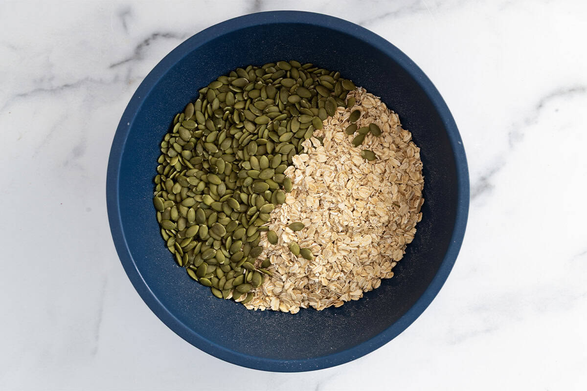 Ingredients for olive oil granola in blue bowl before mixing.