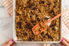 Olive oil granola on baking sheet with spatula.