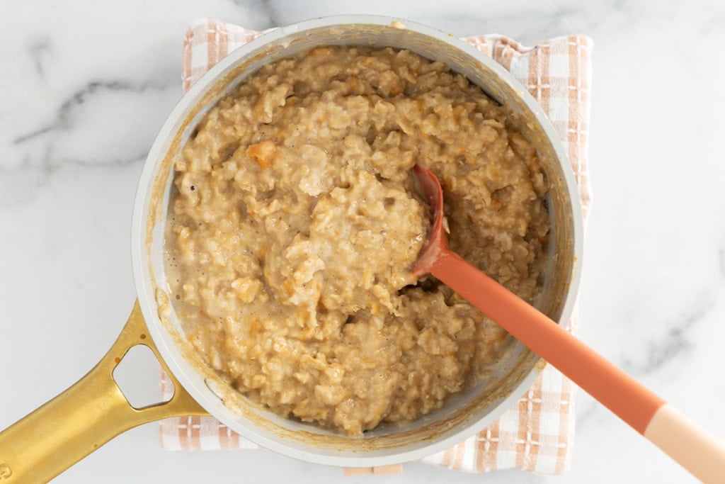 Sweet potato oatmeal in pot with red spoon.