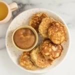 Apple oatmeal pancakes on white plate with applesauce.