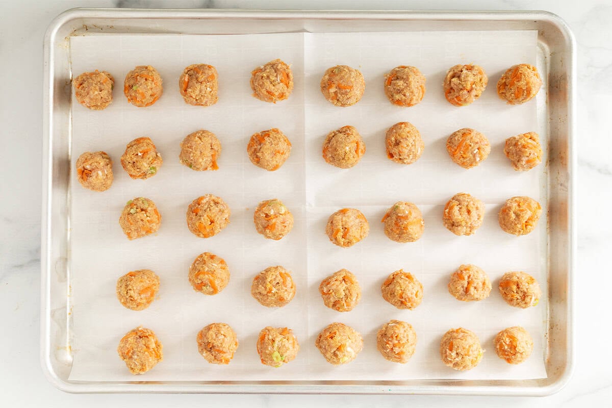 Asian chicken meatballs on baking sheet before baking.