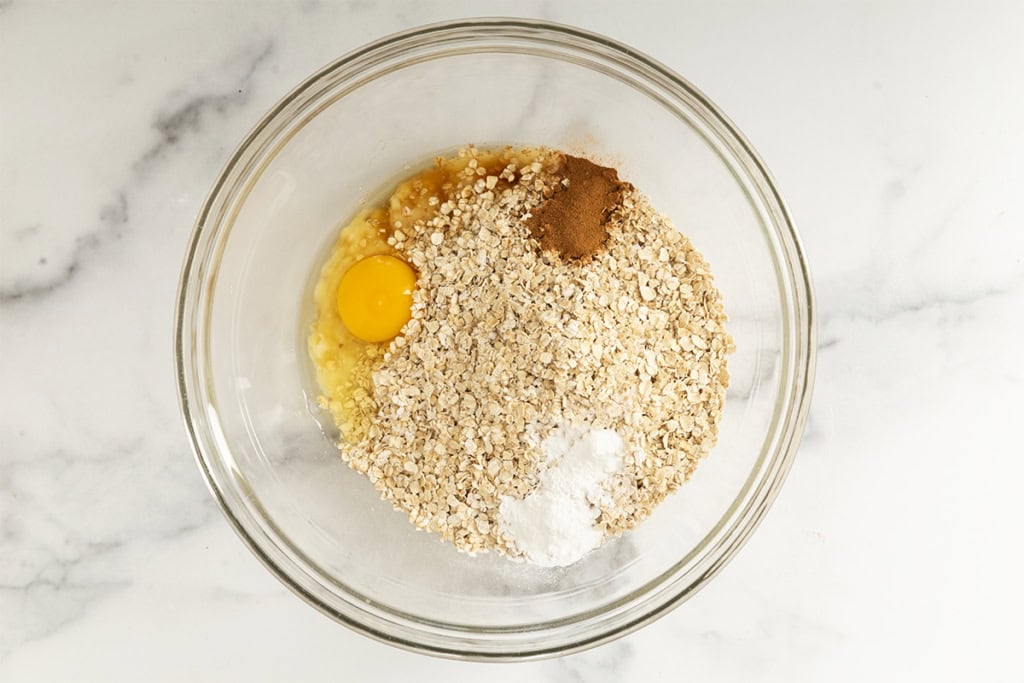 Ingredients for banana oatmeal cookies in glass bowl.