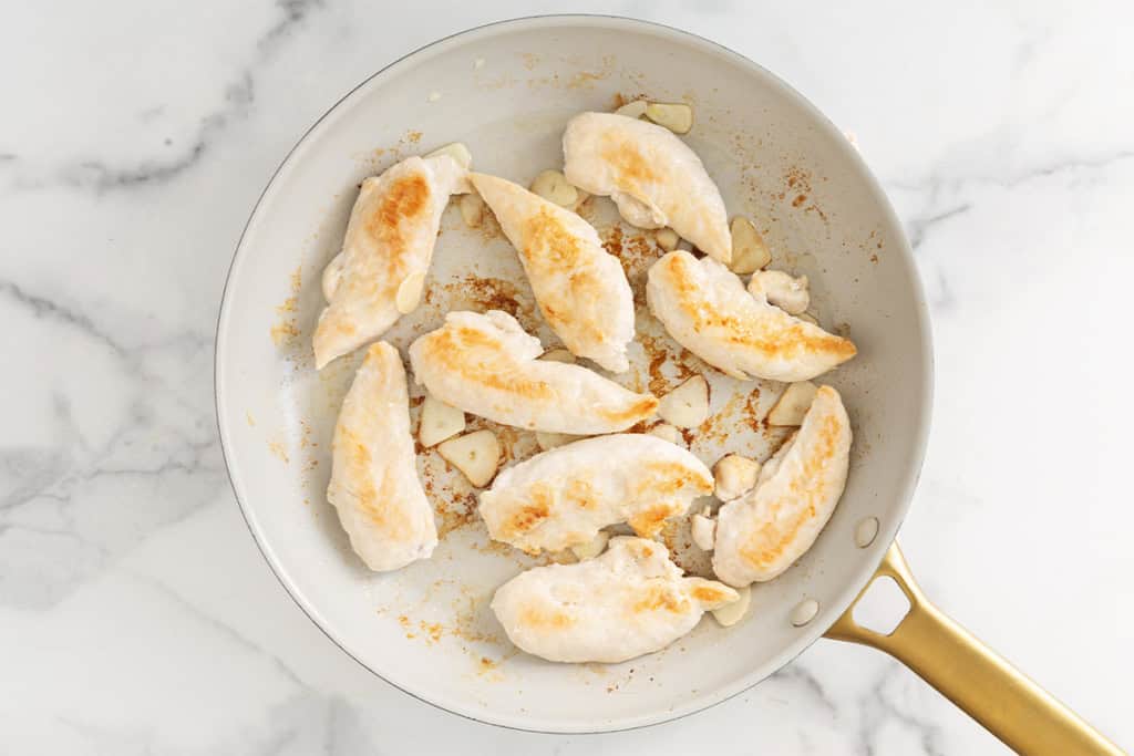 Chicken in frying pan after flipping for pan seared chicken.