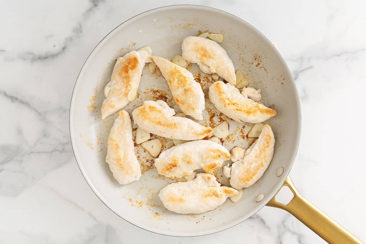 Chicken in frying pan after flipping for pan seared chicken.
