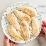 Pan seared chicken on plate with hands holding plate.