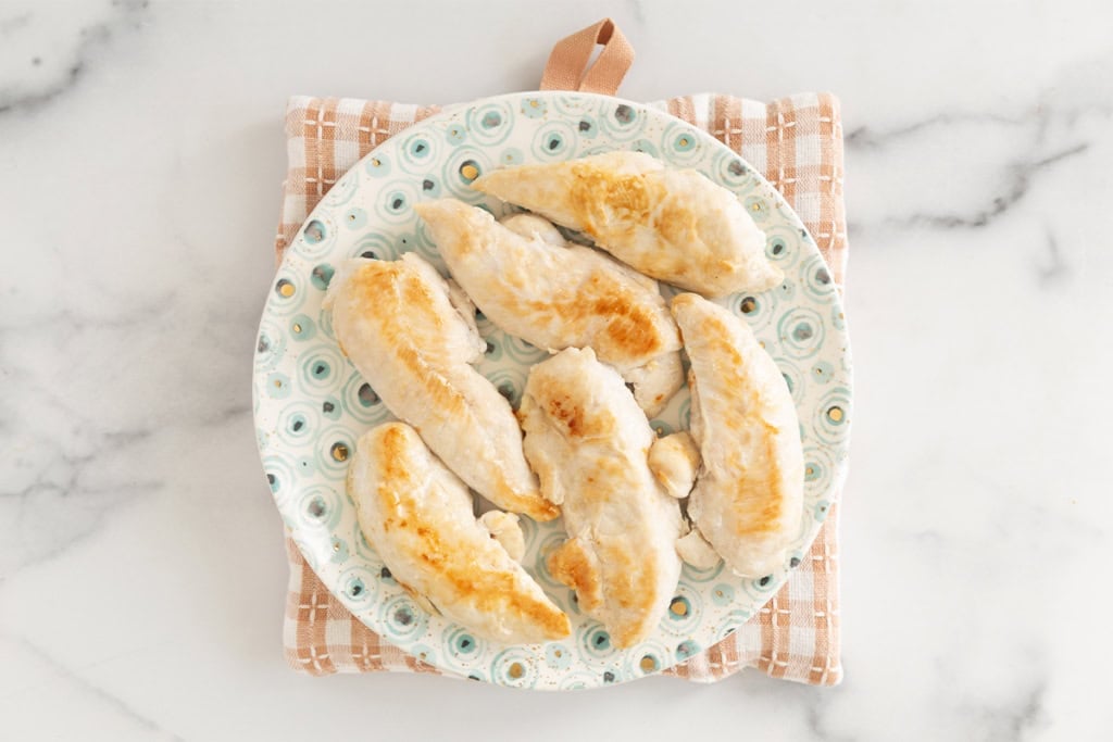 Pan seared chicken on plate sitting on hot pad.