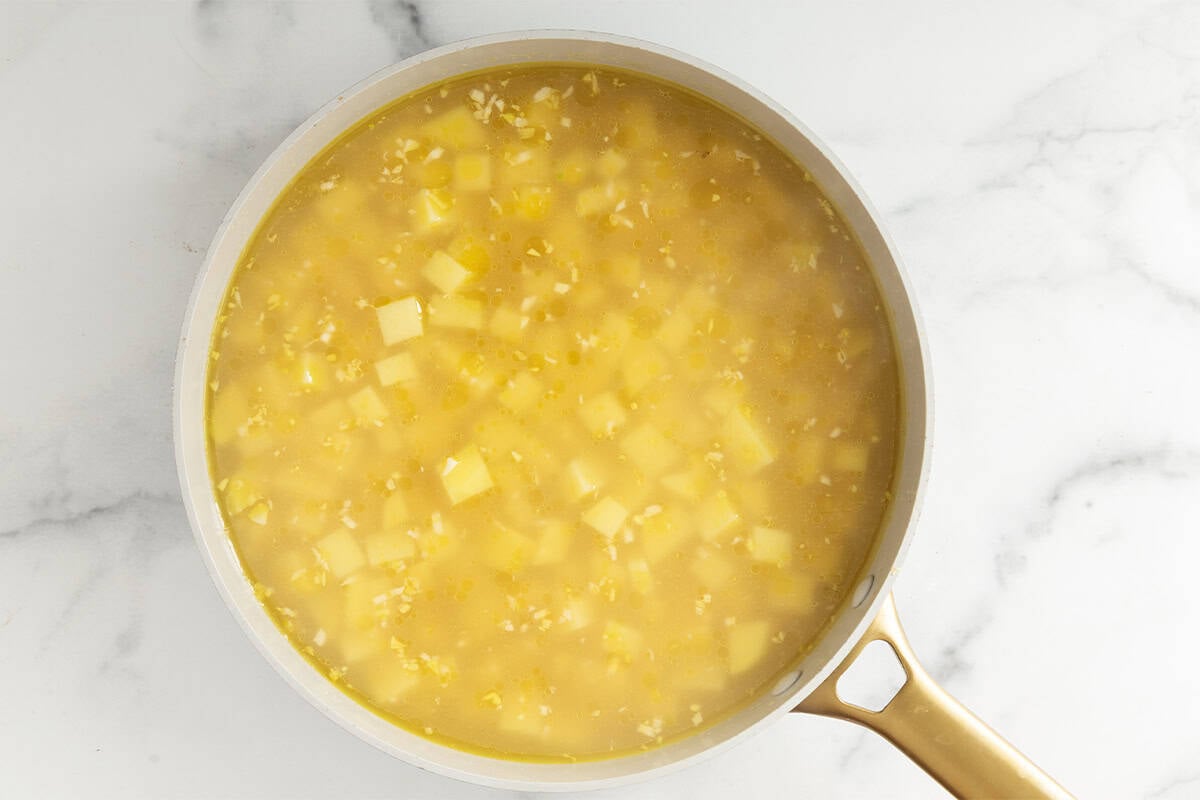 Broth and potatoes in pot for vegetable soup.