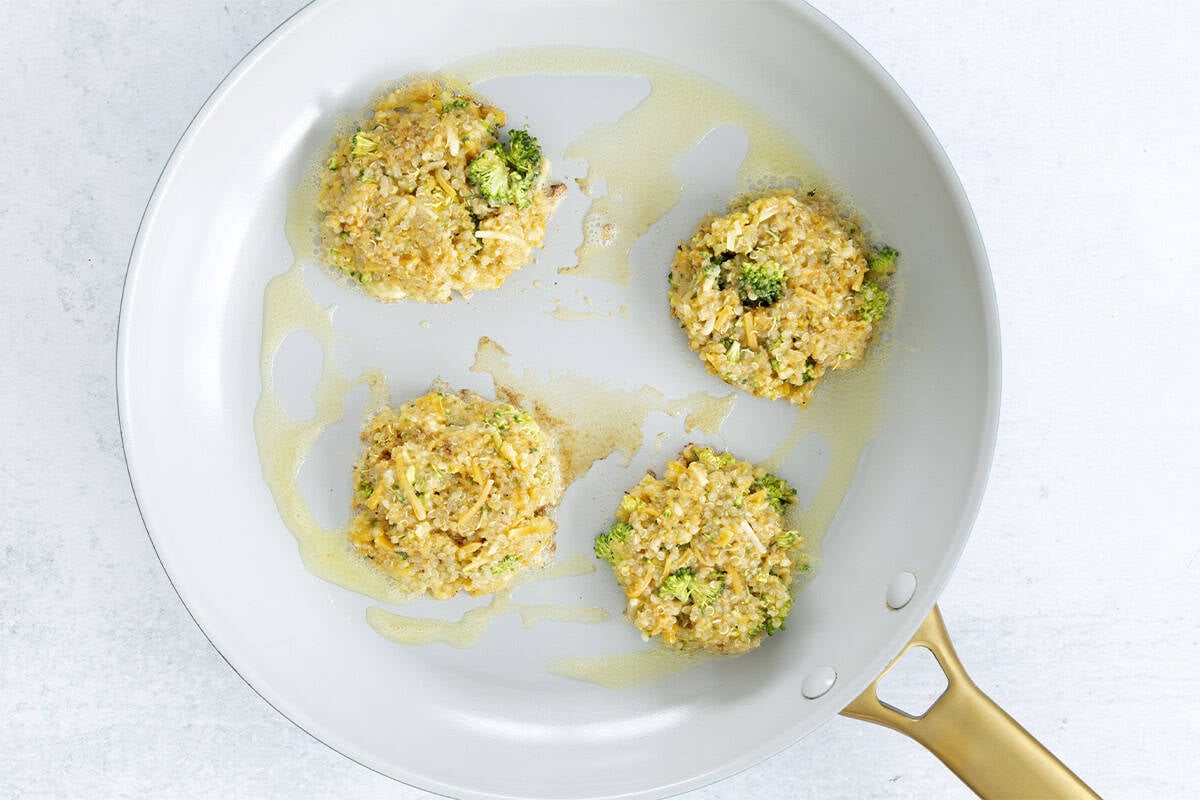 Quinoa patties in pan before flipping.