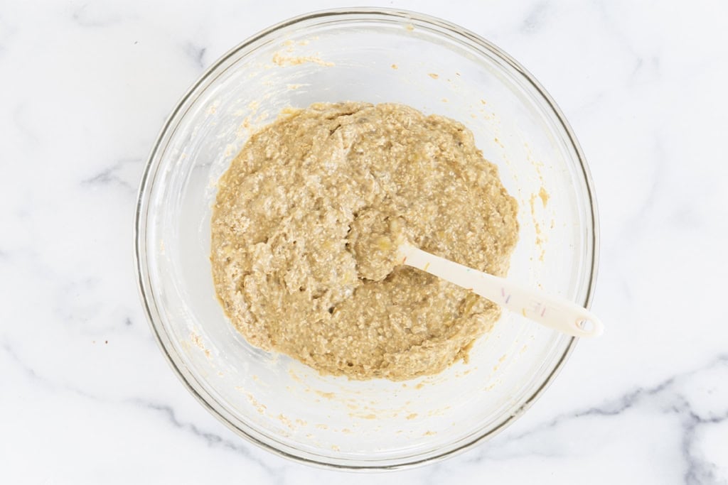 Batter for banana oatmeal bars in glass bowl with spoon.