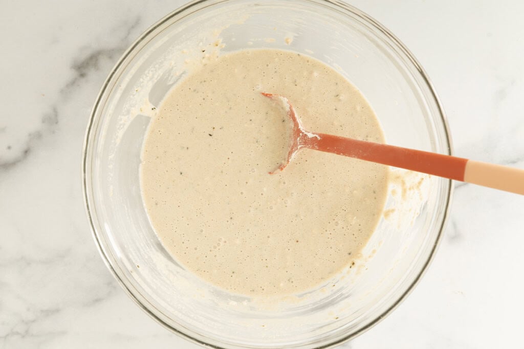Coconut overnight oats mixture in glass bowl with spoon.