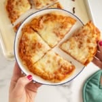 No knead pizza dough pizza on white plate in four slices.