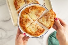 No knead pizza dough pizza on white plate in four slices.