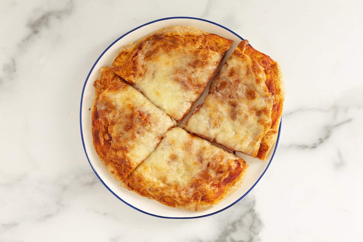 No knead pizza dough pizza on white plate in four slices.
