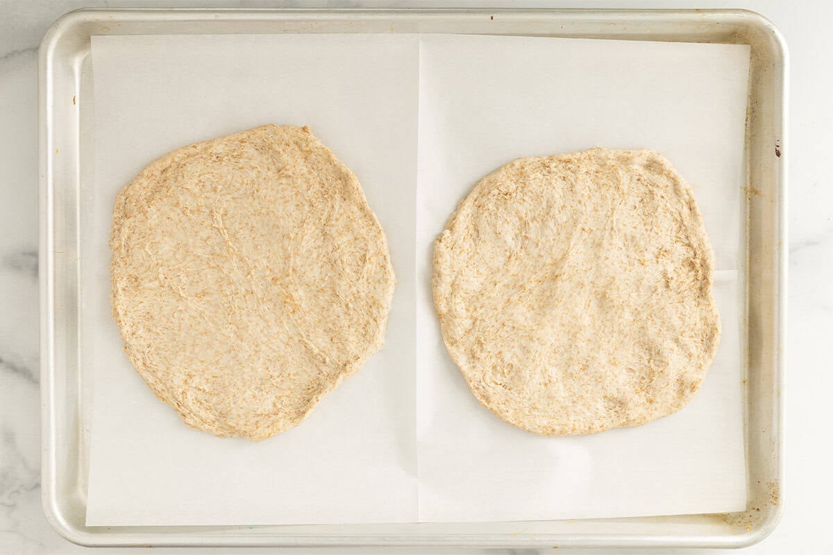 two rounds of no knead pizza dough on baking sheet.