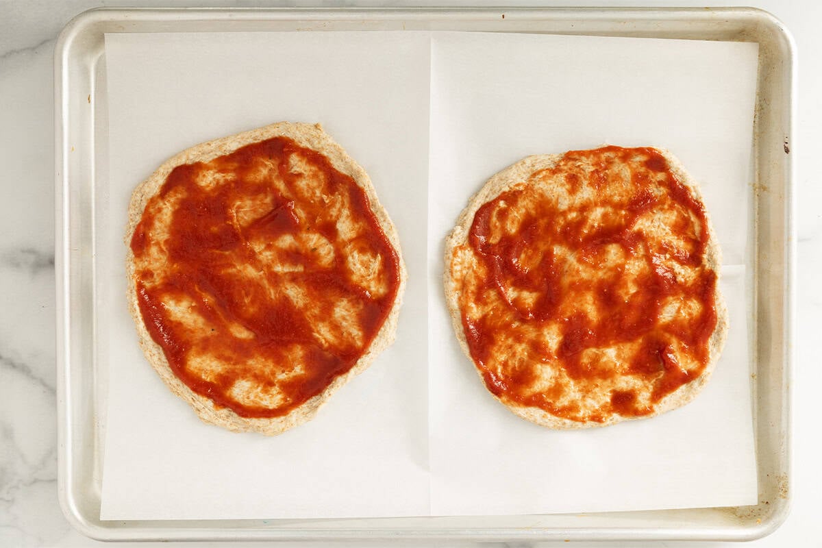 No knead pizza dough with sauce on baking sheet.