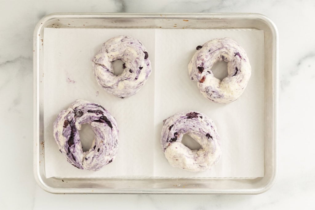 Blueberry bagels on baking sheet before baking.