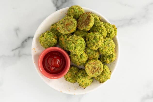 Broccoli cheddar bites on white plate with dip.