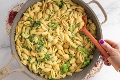 Broccoli cheddar pasta in pot with spoon.
