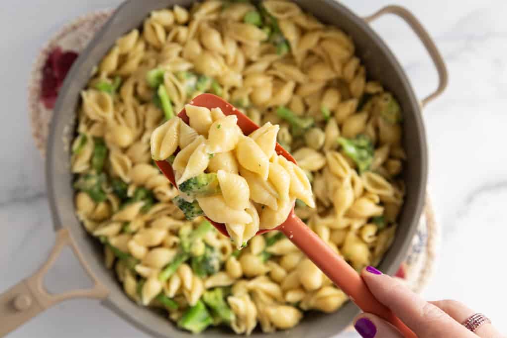 Broccoli cheddar pasta in pot with spoon.