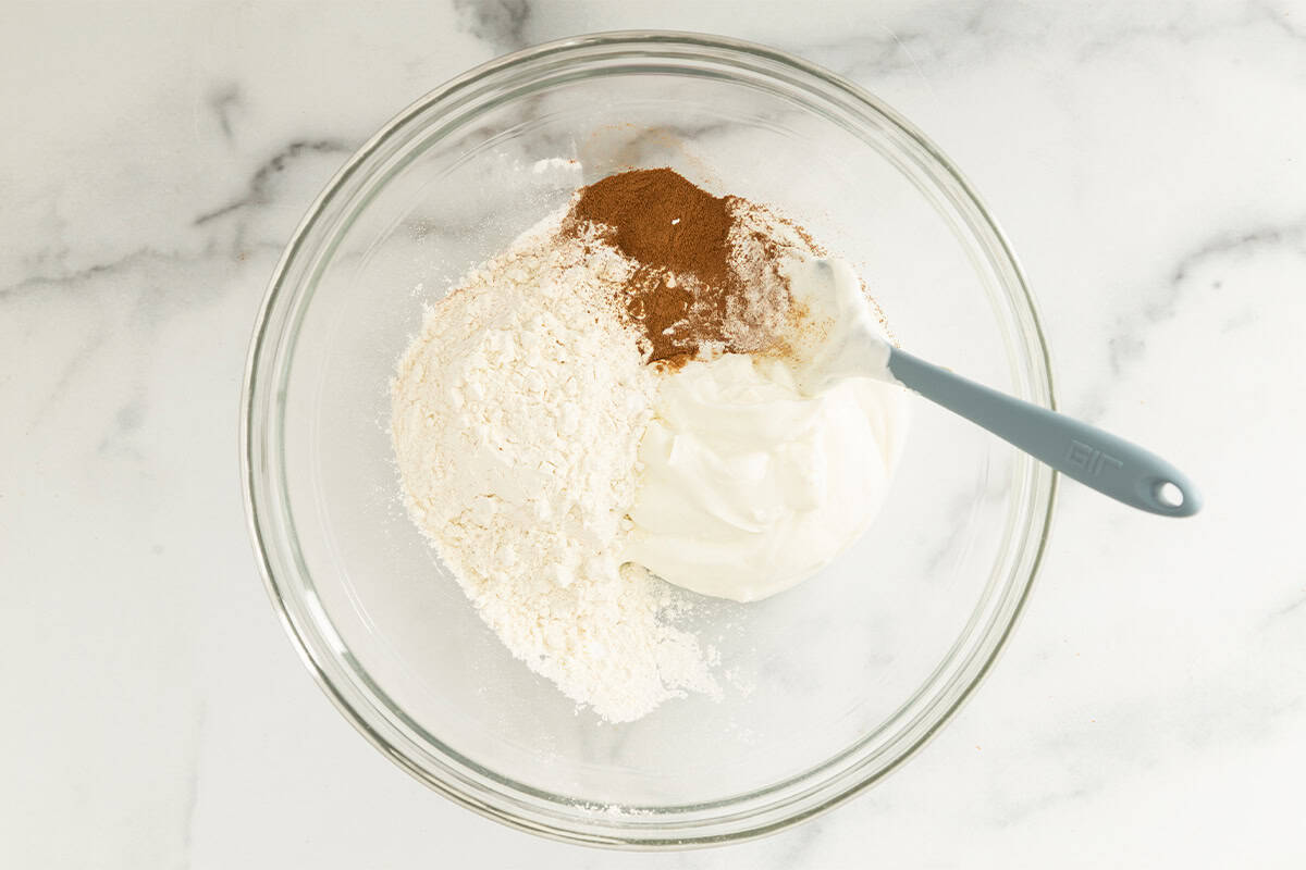 Ingredients for cinnamon bagels in glass bowl before mixing.