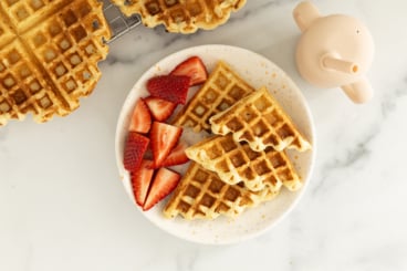 Cottage cheese waffle on white plate with strawberries.