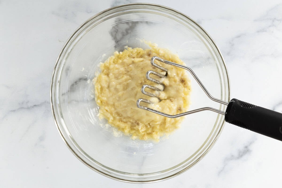 Banana being mashed in glass bowl.