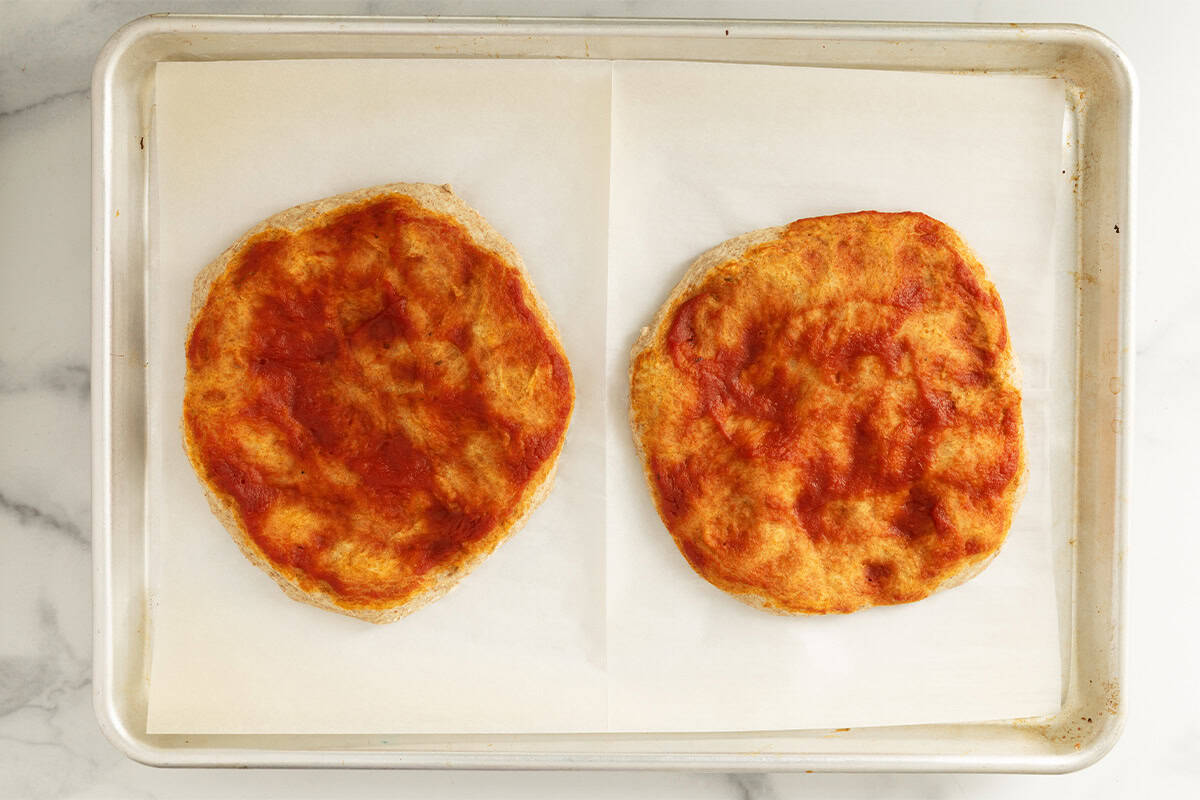 prebaked easy homemade pizzas on baking sheet.