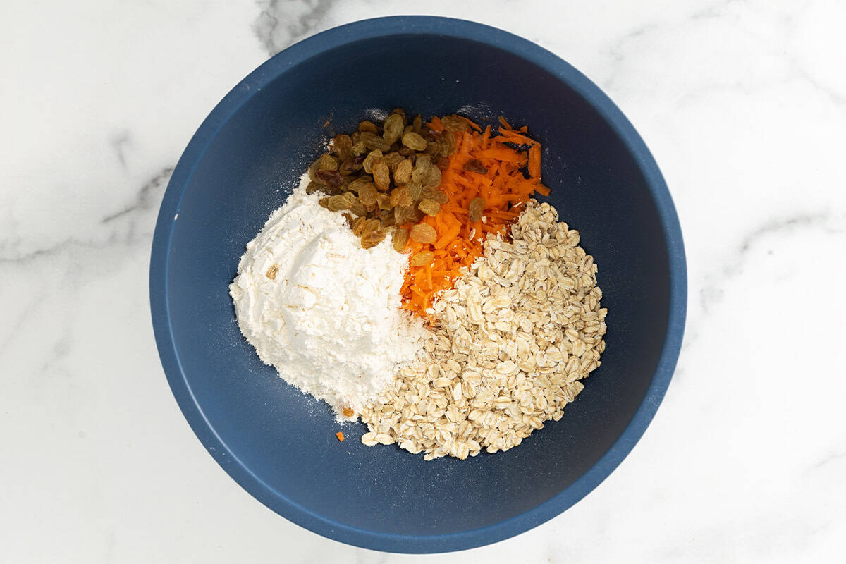 Ingredients for carrot oatmeal cookies in blue bowl.
