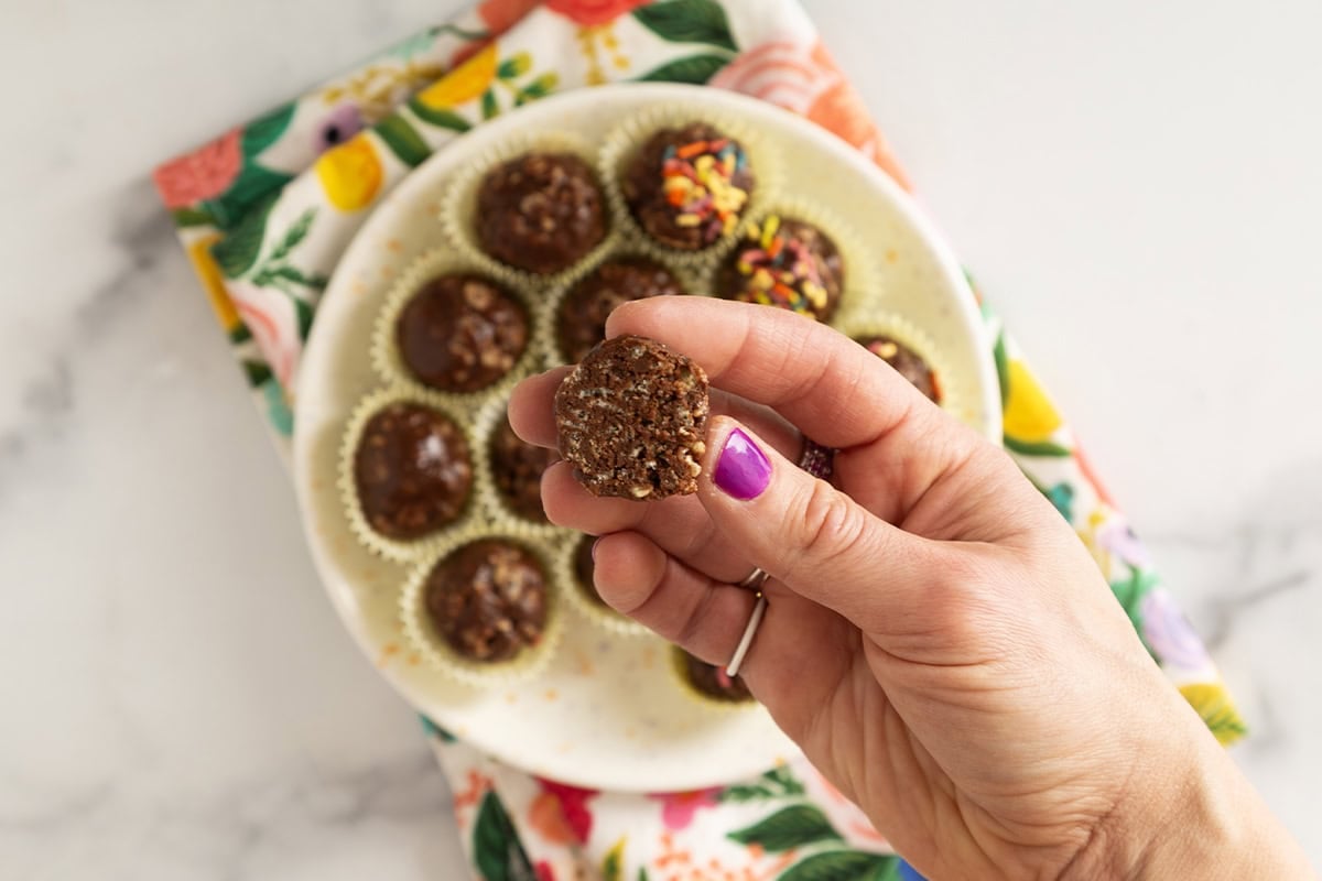 Hands holding chocolate rice crispy ball.