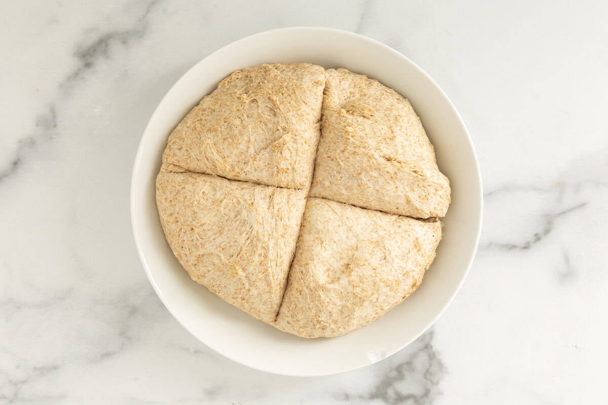 pizza dough cut into fours on white plate.